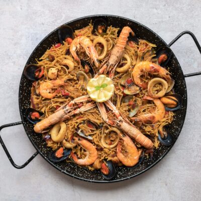A top view shot of delicious Paella with seafood and onion rings
